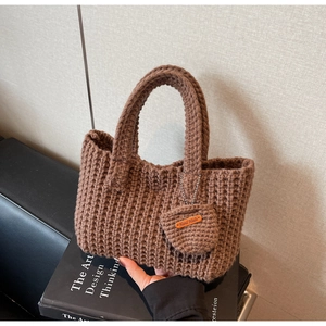 Close-up of a dark brown knit tote bag showing handmade leather tag and woven texture