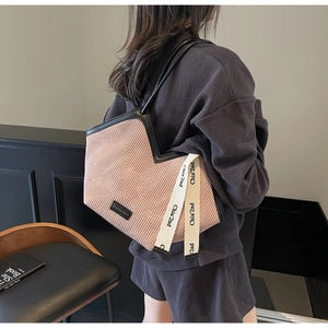 Detail of pink pleated tote bag with black leather straps and woven logo pendant
