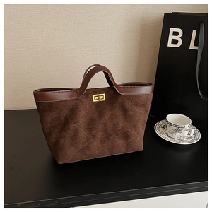 Close-up of quilted suede tote bag with golden lock detail and smooth leather handles