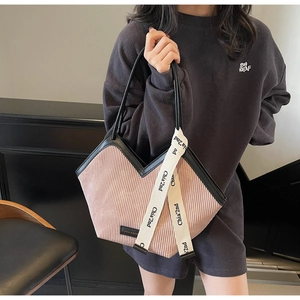 Detail view of pink pleated tote bag with black straps and branded decorative ribbon