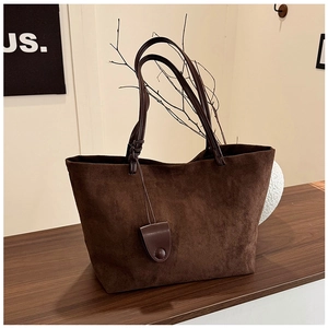 Close-up of matte brown tote bag on dark wood surface with minimalist art decor