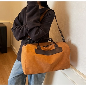 Detail view of a vintage suede travel bag with dark brown leather straps and metal zippers