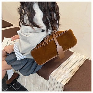 Detail view of brown suede shoulder bag featuring a rectangular silhouette and leather strap