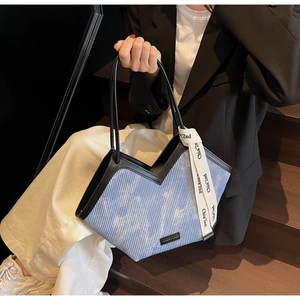 Detail of light blue corduroy tote bag with black leather trim and decorative silk scarf