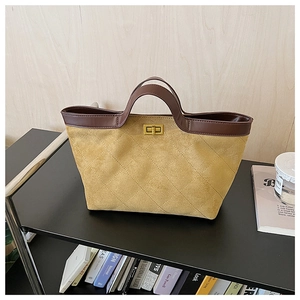 Detail view of mustard yellow suede tote with large diamond stitching and metal twist lock