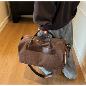 Close-up of the brown duffel bag with leather handles and metallic zipper details