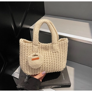 Detail of cream woven tote bag with a Hand Made leather tag on a mini pouch accessory