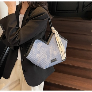 Detail of light blue corduroy tote bag with V-shaped design and decorative ribbon