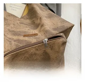 Detail shot of smooth silver metal zipper and textured brown suede surface on the tote bag
