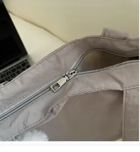 Detailed macro shot of smooth silver metal zipper on taupe nylon tote bag texture