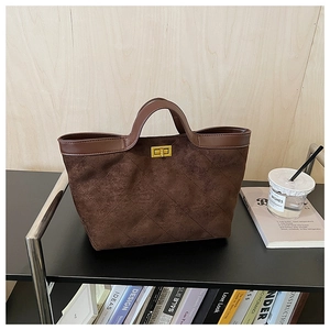 Close-up of quilted brown suede tote bag with leather trim and gold twist lock
