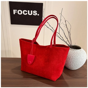 Detail of red faux suede tote bag featuring a minimalist texture and elegant shoulder straps