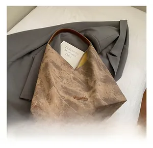 Detail of vintage brown tote bag with marble texture on a grey blazer and white bed