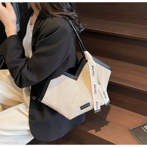 Detail showing the creamy white pleated texture and branded ribbon on this tote bag
