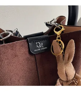 Detailed close-up of dark brown suede bucket bag with a cute knit rabbit keychain