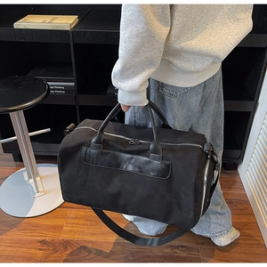 Detail of black travel bag with dual handles and embossed leather logo strap accent