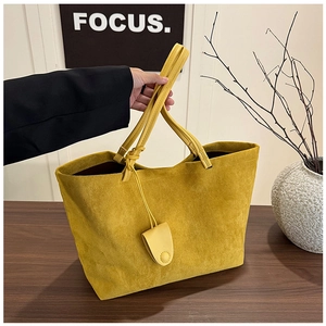 Detail of lemon yellow suede tote bag featuring long knotted straps and a teardrop charm