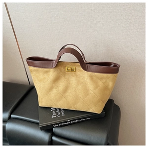 Detail of quilted suede tote bag featuring a golden twist lock and dark leather handles