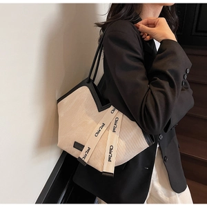 Detailed side view of a large cream tote bag featuring pleated texture and logo webbing
