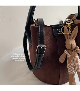 Detail of brown suede bucket bag featuring adjustable strap and a cute bunny pendant