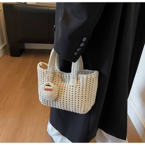 Close-up of handmade beige woven tote bag with chunky knit texture and leather tag