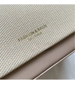 Dettaglio del tessuto in tweed a contrasto e pelle marrone con logo dorato