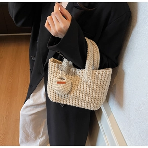 Close-up of cream hand-woven bucket bag with textured stitching and handmade leather tag