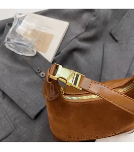 Détail de la boucle en métal doré et texture daim marron sur un sac bandoulière