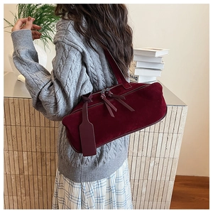Close-up of a burgundy suede pillow bag worn over the shoulder with retro French style