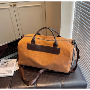 Detail of travel duffel bag showing brown faux leather texture and durable side handles