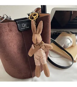 Detail of cute knitted bunny charm with ribbon on a brown matte leather bucket bag
