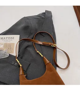 Détail de la boucle métallique réglable sur le sac bandoulière en daim et cuir marron