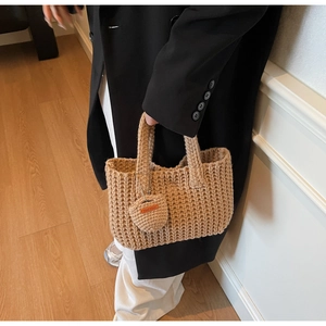 Detailed macro view of khaki hand-woven tote bag texture with heart-shaped handmade charm