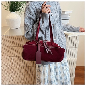 Detail shot of vintage burgundy frosted suede shoulder bag with elegant tassel and charm