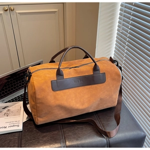 Close-up of orange duffel bag with leather trim and NOCO BAG brand stamp