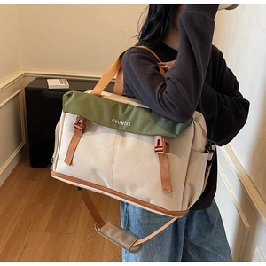 Detail of canvas travel bag featuring olive green flap and adjustable orange strap
