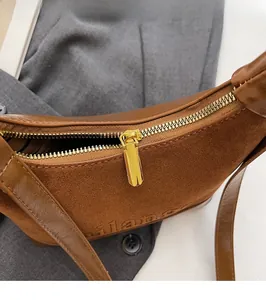 Détail du sac croissant marron avec zip doré et logo Milano embossé sur le daim doux
