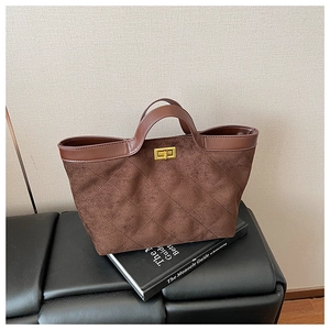 Detail of vintage brown suede tote bag featuring a gold twist lock and leather trim handle