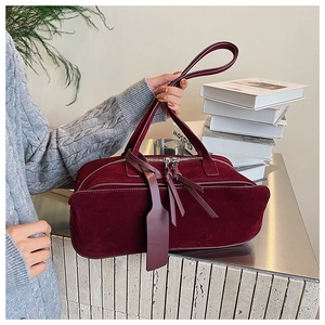 Detailed close-up of burgundy frosted suede pillow bag with long leather zipper pulls