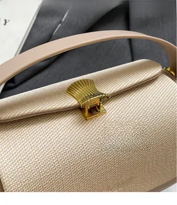 Dettaglio ravvicinato della chiusura a conchiglia dorata su borsa beige intrecciata