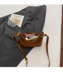 Détails montrant la grande capacité intérieure du sac à bandoulière en daim marron