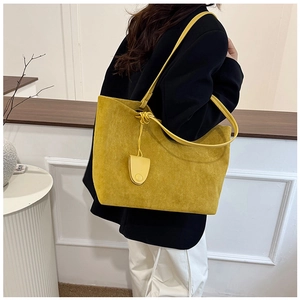 Close-up of yellow frosted faux suede tote bag with slim straps and side tassel detail