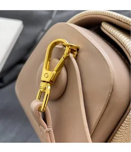 Dettaglio della chiusura in metallo dorato e trama intrecciata su borsa in pelle beige