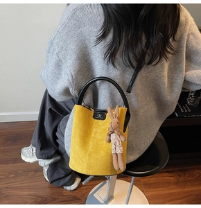 Model view of yellow suede bucket bag with DM logo and cute rabbit charm pendant