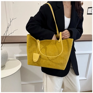 Detail of yellow frosted suede tote bag with slim shoulder straps and hanging charm