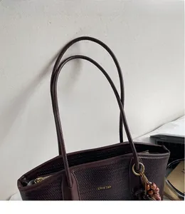 Detail of woven texture dark coffee tote bag with shoulder straps and beaded tassel