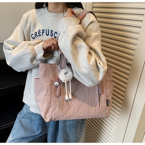Detail of dusty pink nylon tote bag showing side pocket, drawstring and plush charm