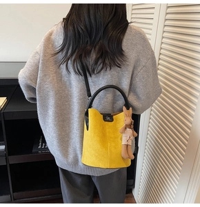 Detail of yellow matte bucket bag with brand logo and cute bunny pendant charm