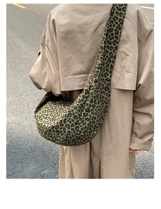 Detail of large leopard print suede dumpling bag with wide shoulder strap on model