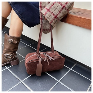 Close-up of a vintage dark brown suede pillow bag with dual straps and zipper detail